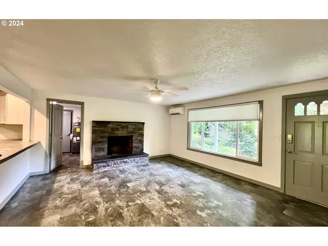a view of an empty room with a fireplace and a window