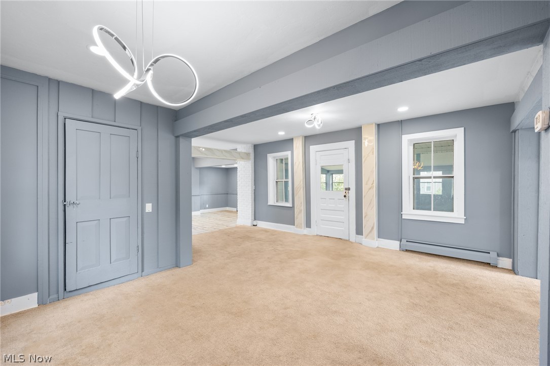 39016 Detroit Road Avon, OH 44011 - Photo 2 of 36 Empty room featuring light colored carpet, a baseboard radiator, and a chandelier