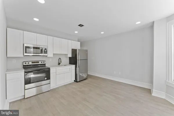 a kitchen with stainless steel appliances a stove a microwave and white cabinets