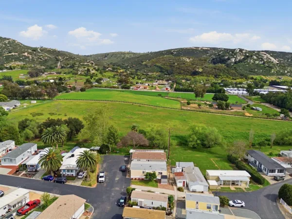 an aerial view of residential houses with outdoor space and trees