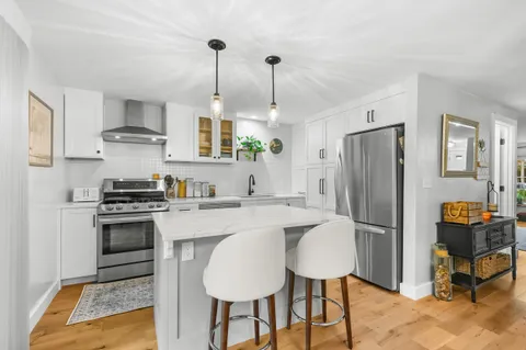 a kitchen with stainless steel appliances granite countertop a stove refrigerator and chairs