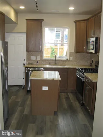 a kitchen with stainless steel appliances granite countertop a stove a sink a refrigerator and a microwave