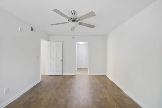 an empty room with wooden floor and a ceiling fan