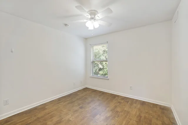 an empty room with windows and fan