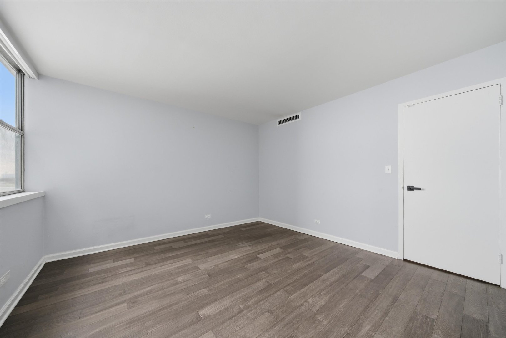 6301 North Sheridan Road, Unit 14G Chicago, IL 60660 - Photo 12 of 22 a view of an empty room with wooden floor and a window