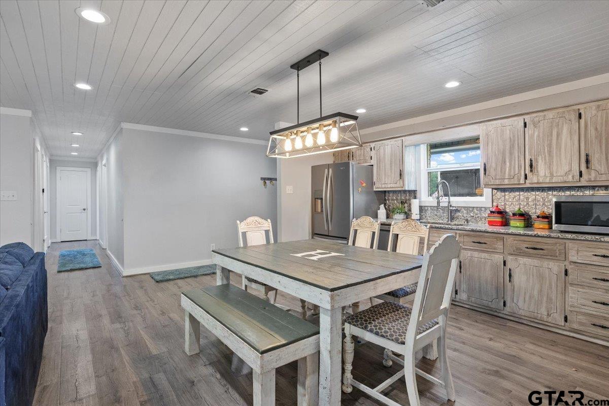 594 County Rd NE 2120 Talco, TX 75487 - Photo 12 of 36 a kitchen with granite countertop a stove a sink dishwasher a dining table and chairs with wooden floor