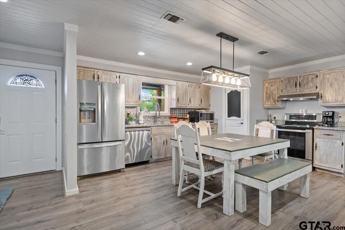 594 County Rd NE 2120 Talco, TX 75487 - Photo 9 of 36 a kitchen with stainless steel appliances granite countertop a refrigerator a stove a sink dishwasher a dining table and chairs with wooden floor