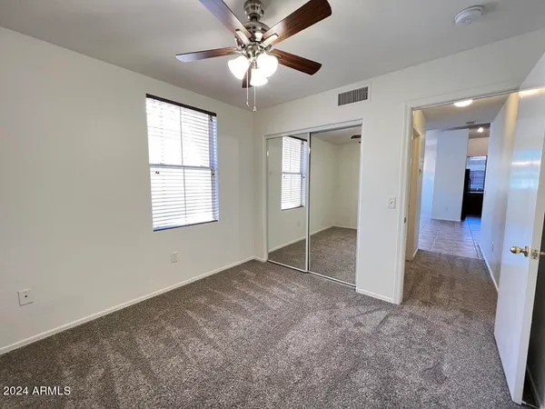 an empty room with a window and chandelier fan