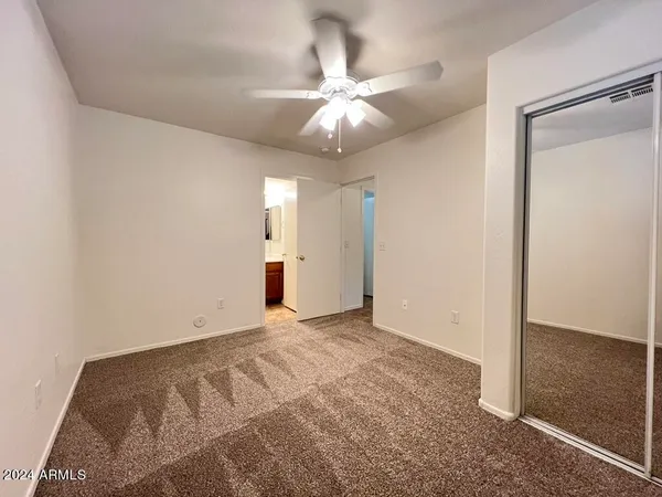an empty room with a chandelier fan and closet