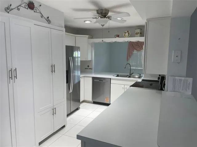 a close view of a refrigerator in kitchen and an empty room with wooden floor