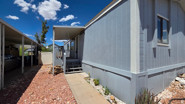 1450 North Dixie Downs Road, Unit 51 St. George, UT 84770 - Photo 17 of 25 Light blue exterior siding with white trim, covered front entry, and a dedicated carport