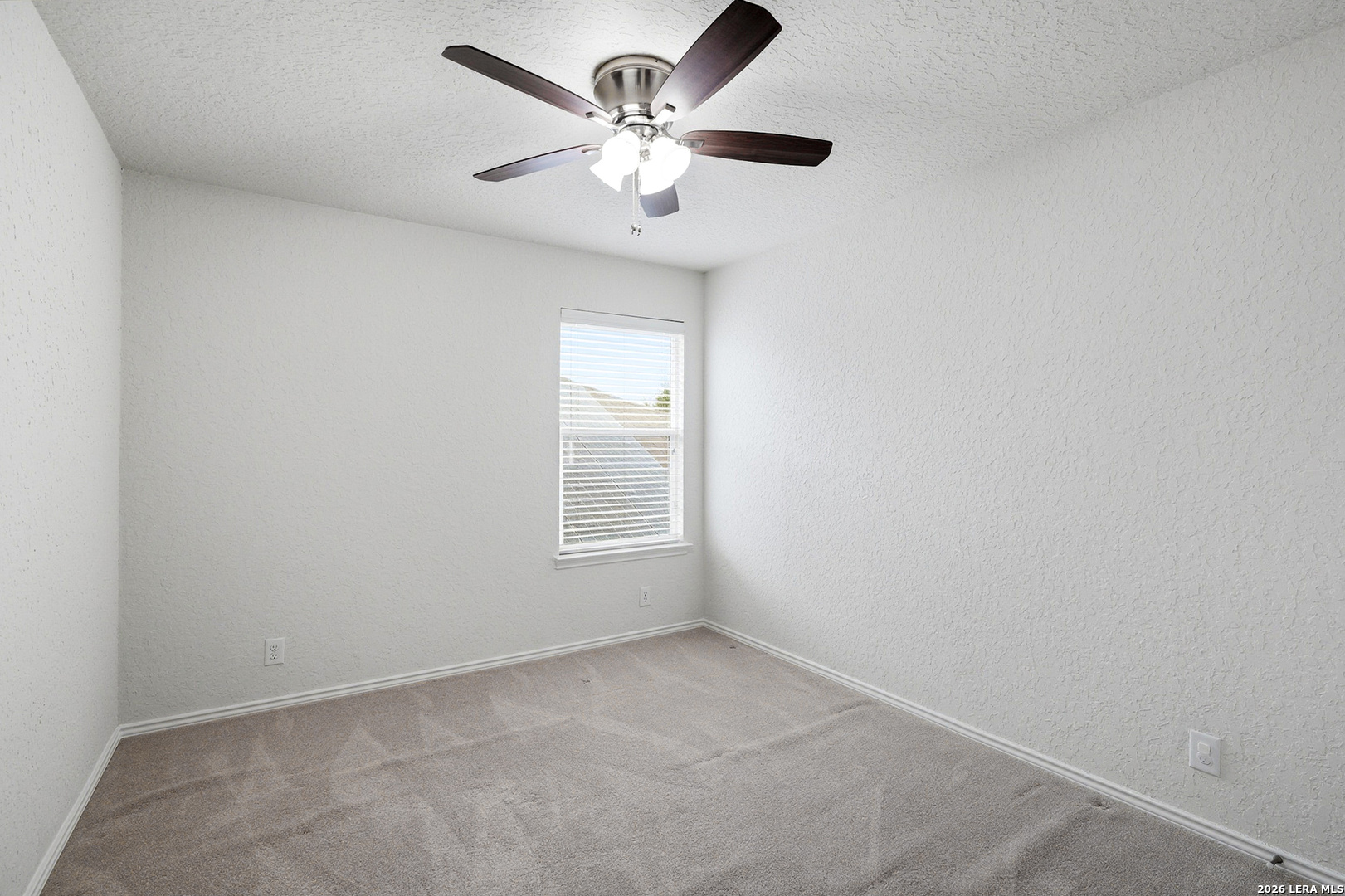 9519 Gold Stage Road San Antonio, TX 78254 - Photo 19 of 25 an empty room with a chandelier fan and windows