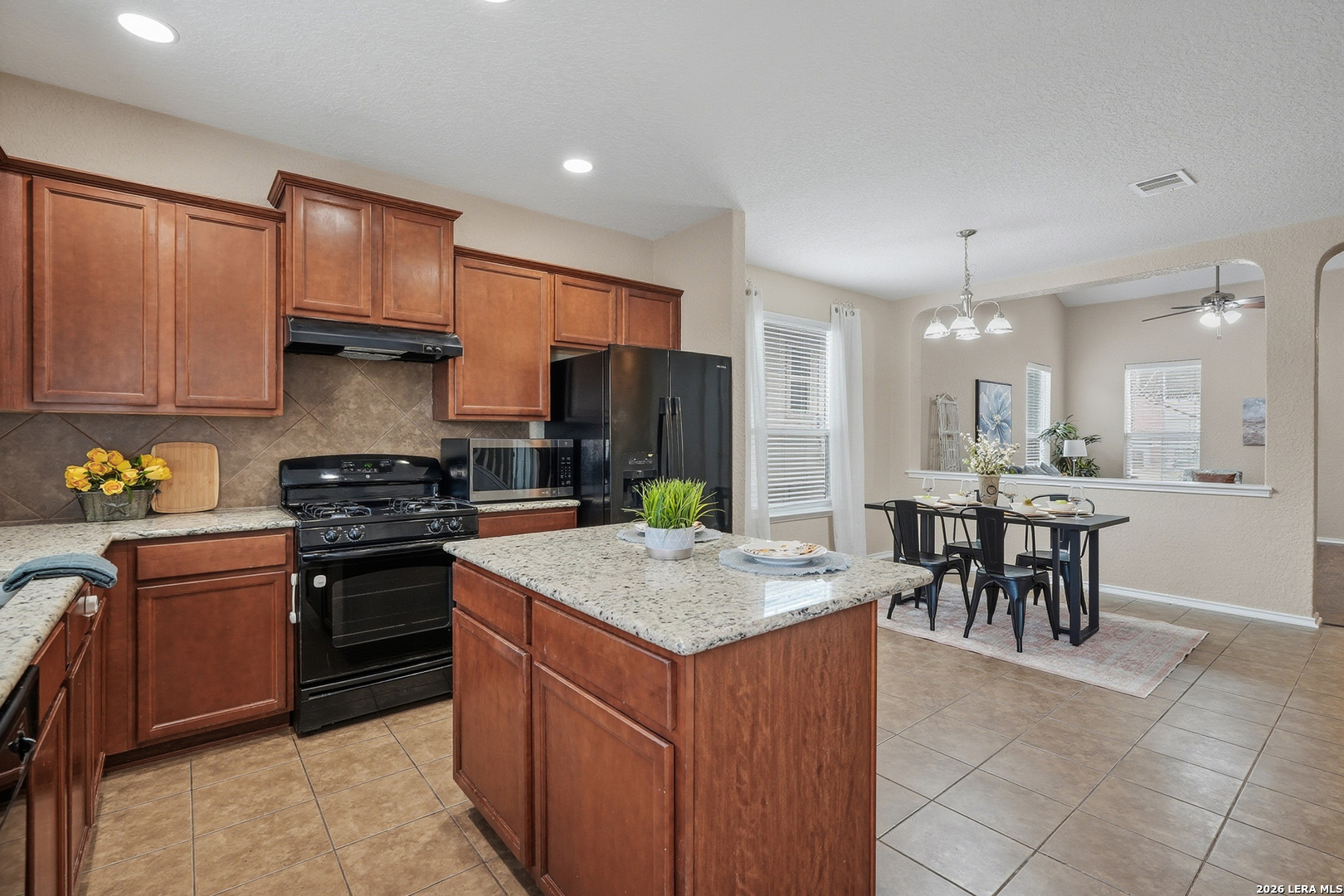9519 Gold Stage Road San Antonio, TX 78254 - Photo 6 of 25 a kitchen with a stove a sink a refrigerator a dining table and chairs