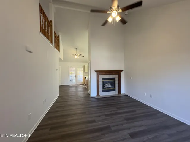 a view of an empty room with wooden floor and a fireplace