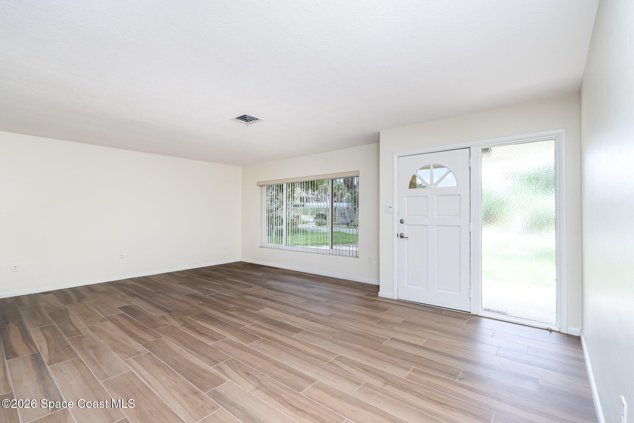 115 Gary Lane Cocoa, FL 32922 - Photo 2 of 29 a view of an empty room with wooden floor and a window