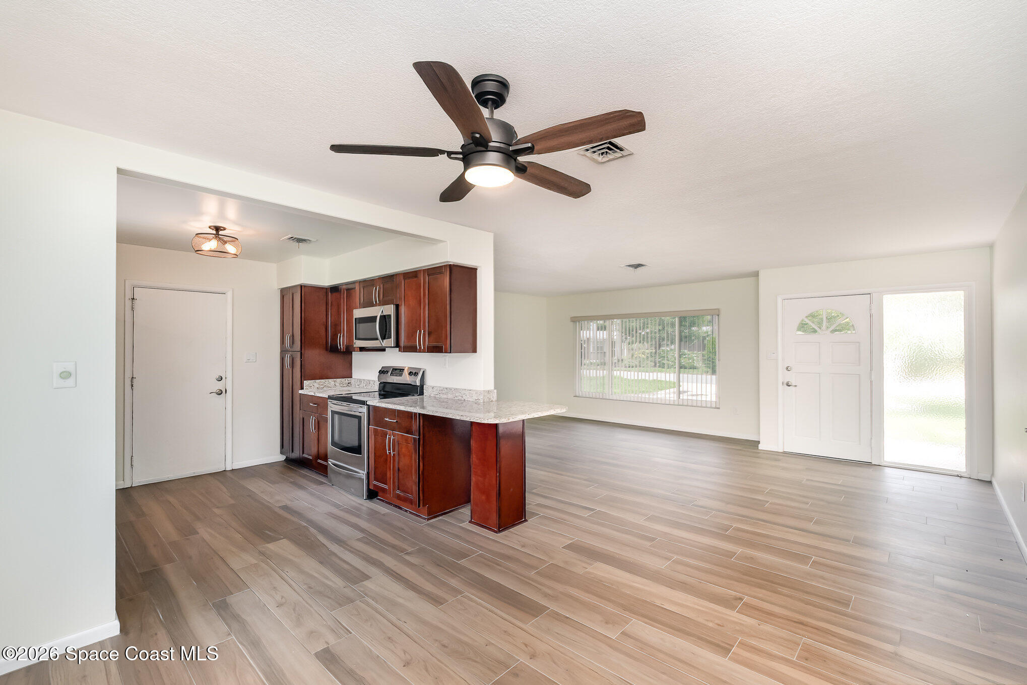 115 Gary Lane Cocoa, FL 32922 - Photo 7 of 29 a view of a kitchen with wooden floor and a ceiling fan