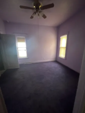 an empty room with a window and a ceiling fan