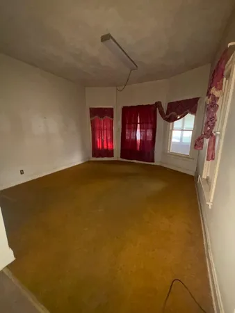 a view of an empty room with window and fireplace