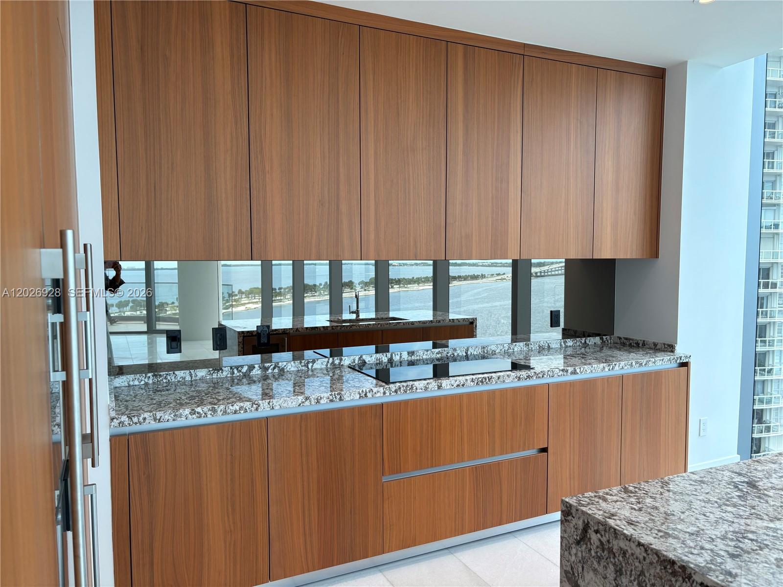 175 Southeast 25th Road, Unit 901 Miami, FL 33129 - Photo 8 of 18 a kitchen with kitchen island granite countertop wooden cabinets and a sink