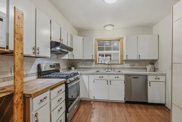 a kitchen with stainless steel appliances granite countertop a sink stove and cabinets