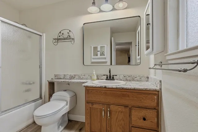a bathroom with a granite countertop toilet sink and mirror