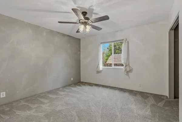 an empty room with windows and fan