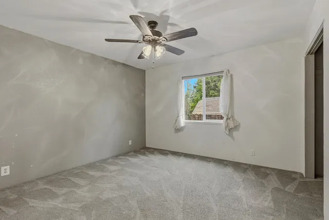 an empty room with windows and fan