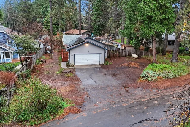 a view of a house with a yard and large trees