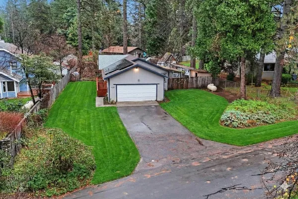 a view of a house with a small yard and a large tree