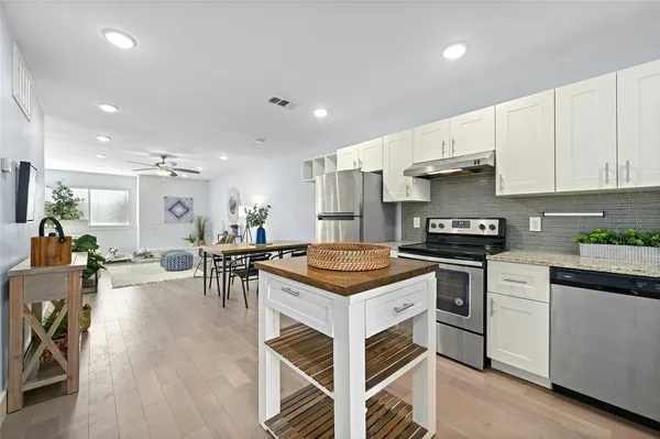 a kitchen with stainless steel appliances a stove a sink a stove a refrigerator cabinets and living room view