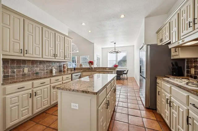 a kitchen with stainless steel appliances granite countertop a stove a sink and a refrigerator