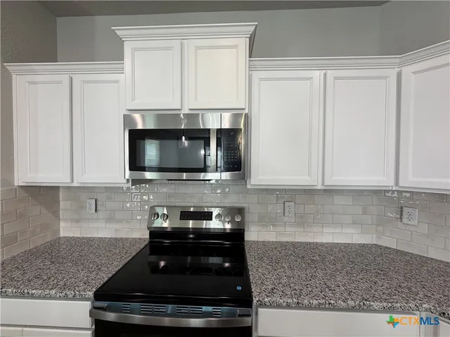 a kitchen with microwave a stove and cabinets