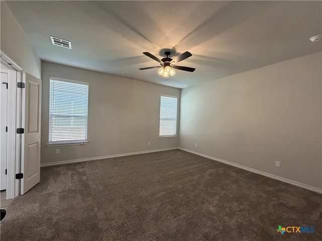 an empty room with windows and fan