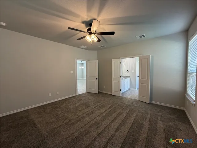 an empty room with closet and a ceiling fan