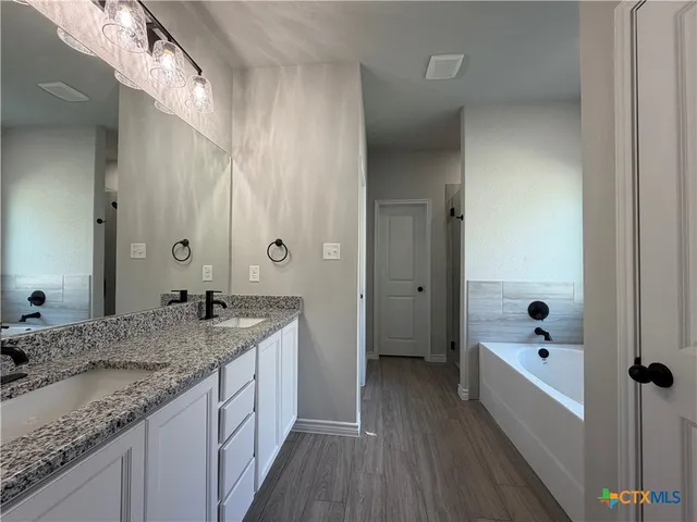 a bathroom with a granite countertop tub sink and mirror