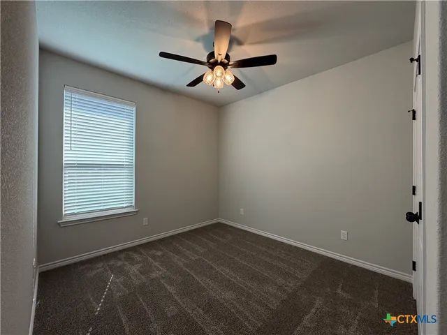 an empty room with a window and a fan
