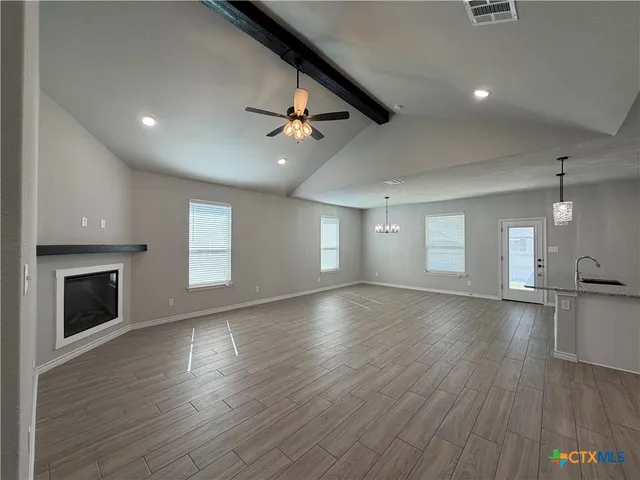 an empty room with wooden floor fireplace and windows