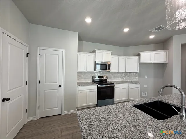 a kitchen with stainless steel appliances granite countertop a stove a sink and a refrigerator