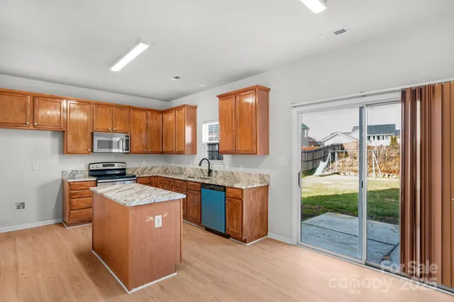 a kitchen with stainless steel appliances granite countertop wooden cabinets a sink and a stove