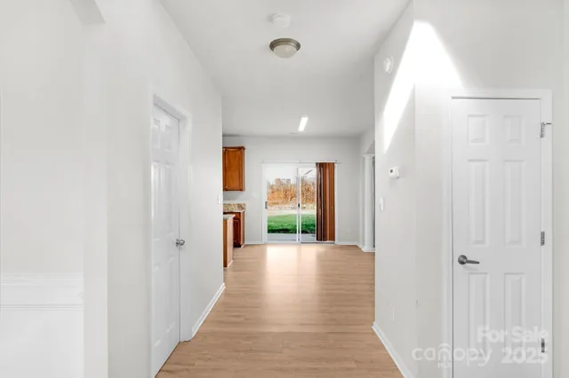 a view of a hallway with wooden floor staircase and a bathroom