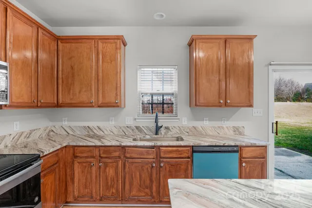 a kitchen with granite countertop wooden cabinets a sink and dishwasher