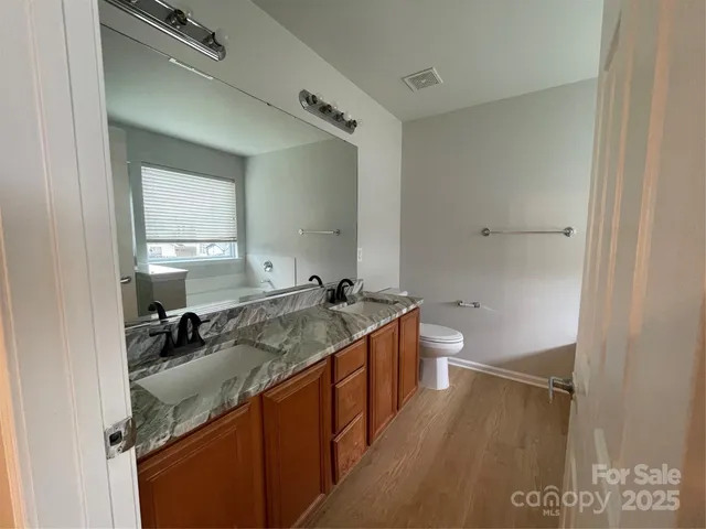 a bathroom with a granite countertop sink a toilet and a mirror