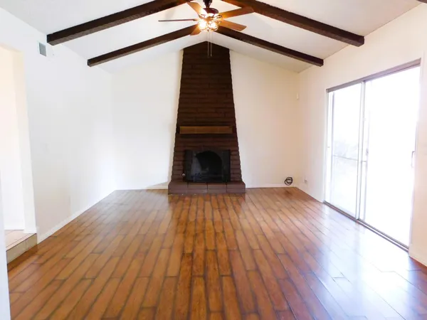 a view of a big room with wooden floor and windows