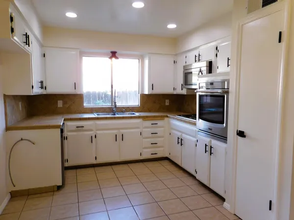 a kitchen with white cabinets a sink dishwasher and a stove with wooden floor