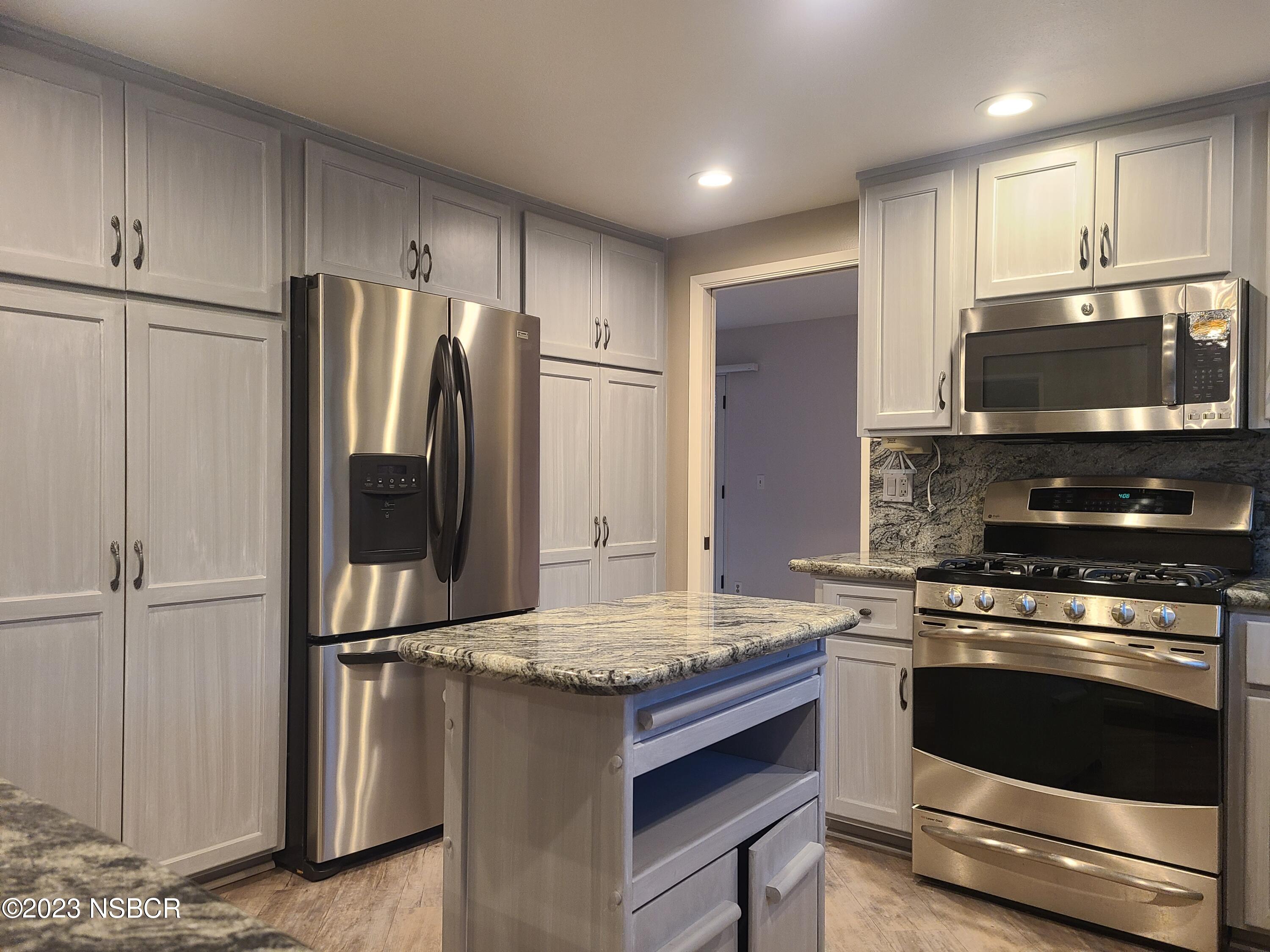 1205 North B Street Lompoc, CA 93436 - Photo 12 of 39 a kitchen with kitchen island granite countertop a stove cabinets and refrigerator