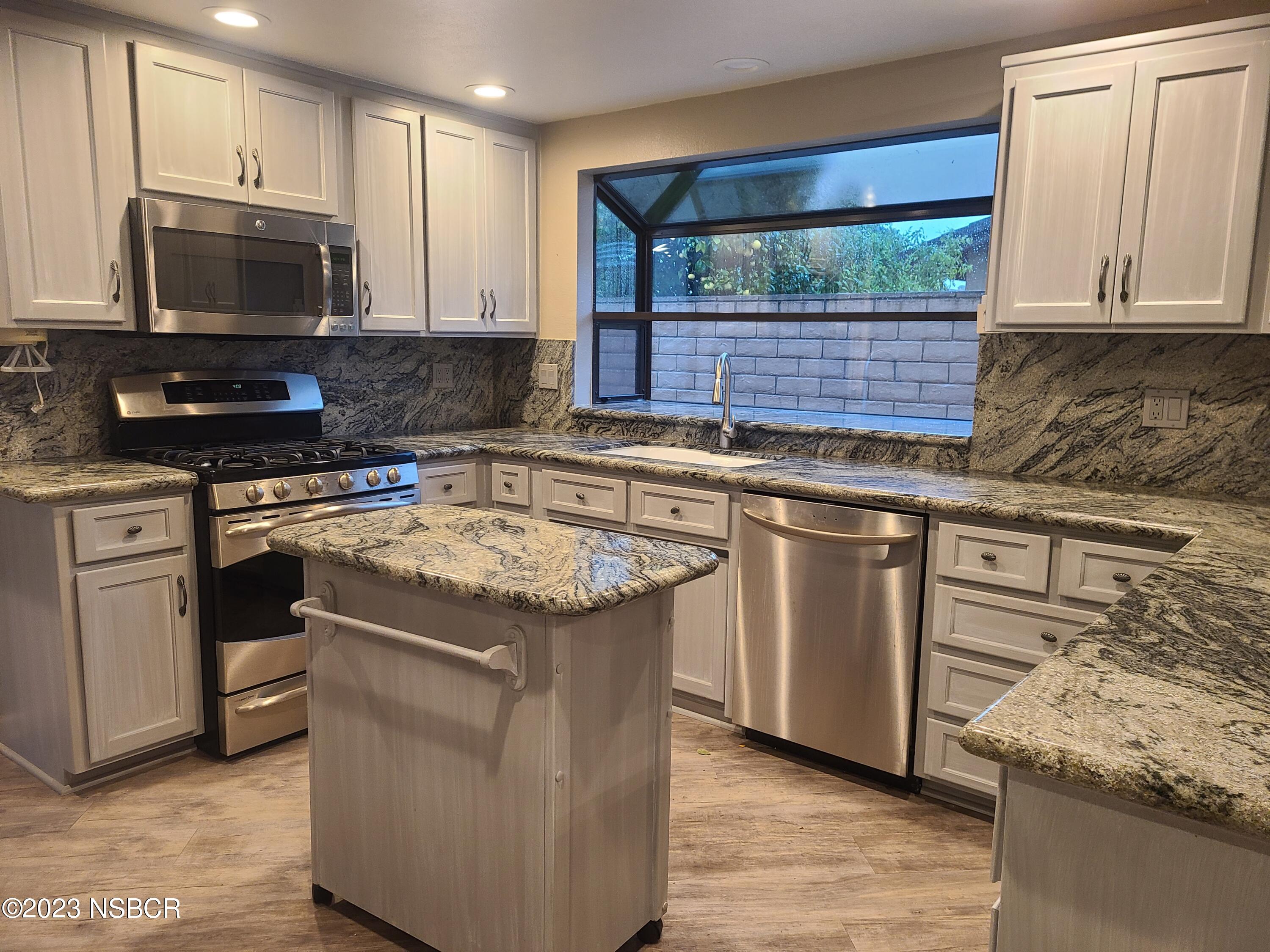 1205 North B Street Lompoc, CA 93436 - Photo 13 of 39 a kitchen with stainless steel appliances granite countertop a stove a sink and a microwave