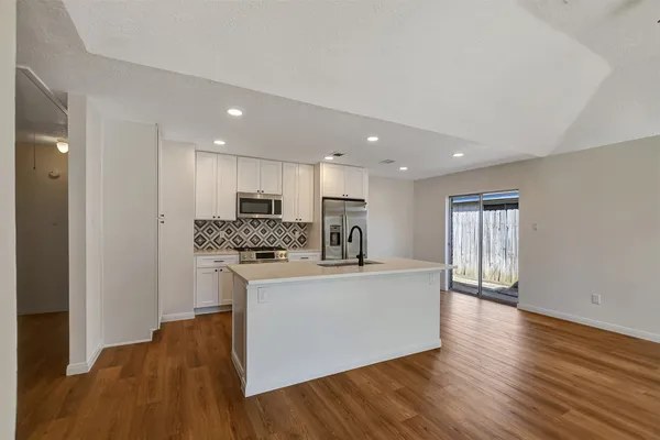 a kitchen with granite countertop cabinets stainless steel appliances and wooden floor