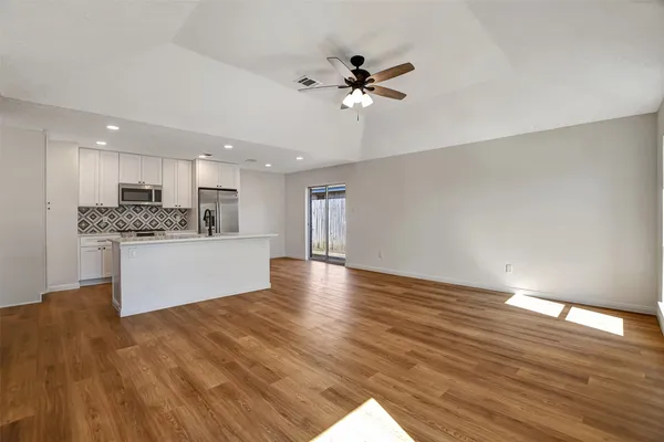 an empty room with wooden floor cabinet and windows