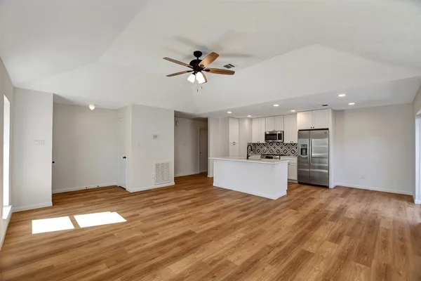 a view of kitchen with stainless steel appliances granite countertop a stove top oven a refrigerator a sink and dishwasher with wooden floor