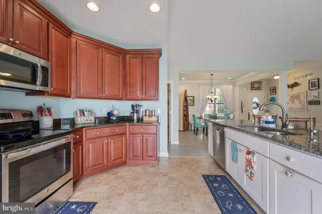 a large kitchen with stainless steel appliances granite countertop a stove top oven a sink dishwasher and a refrigerator with wooden cabinets